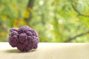 Fresh ripe purple cauliflower. Healthy food on table on defocus autumn background. photo