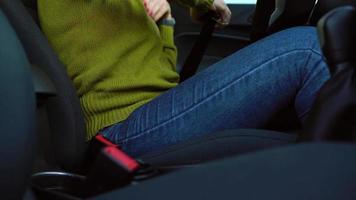 Female hand fastening car safety seat belt while sitting inside of vehicle before driving video