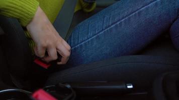 Female hand fastening car safety seat belt while sitting inside of vehicle before driving video