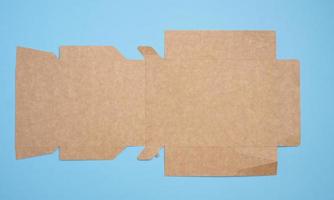 A brown cardboard box in an unfolded state on a blue background, food packaging, merchandise, top view photo