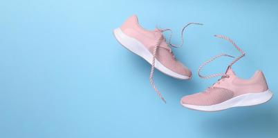 Pink women's sports sneakers with laces levitate on a blue background photo