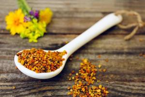 Bee pollen and field flowers on old wooden background. Toned image. photo