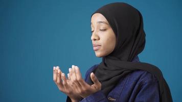 inocente y hermosa musulmán africano mujer en hijab es Orando. fiel africano mujer. africano joven mujer en musulmán hijab Orando, preguntando Alá para bueno deseos, dando gracias. video