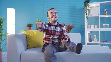 Smiling young disabled man using smartphone at home. Young dwarf man guy holding smartphone device sending sms message at home, playing mobile game, disabled man using apps chatting on social media. video