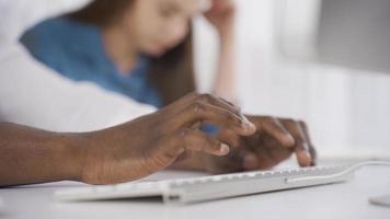 Close-up of African American businessman typing information on keyboard on computer. Mixed race male hands making notes on computer keyboard at table, close-up. Different races and ethnicity concept. video