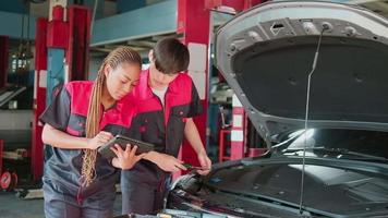 dois profissional automotivo mecânico parceiros Verifica e reparar a ev carro bateria e híbrido motor às uma manutenção garagem, especialista elétrico veículo serviço, e fixação ocupações auto indústria. video