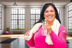 Happy Hispanic Woman with Towel and Bottle of Water Inside Yogo Studio. Some of the elements in this image are . photo