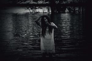 Portrait of asian woman make up ghost face at the swamp,Horror in water scene,Scary at river,Halloween poster,Thailand people photo