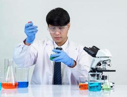 Asian male student scientist in reagent mixing laboratory In a science research laboratory with test tubes of various sizes and microscopes. on the table in  laboratory chemistry lab white background. photo