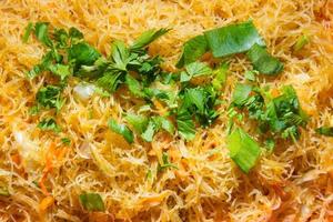 Indonesian traditional cuisine, Fried vermicelli bihun goreng or oseng bihun are sweet and spicy fried vermicelli mixed with eggs and some vegetables, topped with chopped celery leaves photo