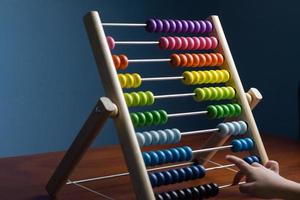 Abacus with colorful beads on blue background, close up, Counts kids learning, kids math class concept, with counting child's hands photo