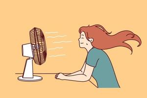 Woman sitting in front of fan enjoying cold wind after walking in hot summer weather or doing housework. Sweaty girl cools herself using electric fan due to sudden warming and climate change vector