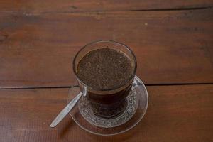 Close up photo a cup of arabica coffee with spoon from high angle. The photo is suitable to use for coffee shop background, menu poster and coffee content media.