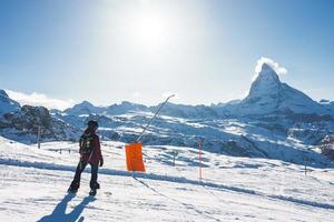 Young man snowboarding in Zermatt ski resort right next to the famous Matterhorn peak. Beautiful sunny day for snowboarding. Winter sports concept. photo