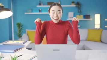 ung asiatisk kvinna ser på bärbar dator ensam på Hem nöjd med de se hon ser på de skärm och leende ser på de kamera, ger en positiv gest med henne hand. video