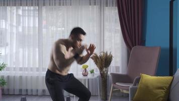 Boxer joven hombre haciendo sombra boxeo a hogar. muscular hombre boxeo de sombra solo a hogar. video