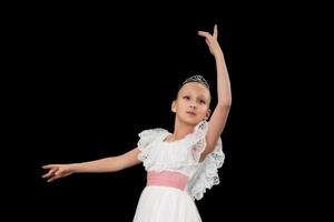 encantador niña bailarina en blanco vestir bailando en negro antecedentes en estudio. foto