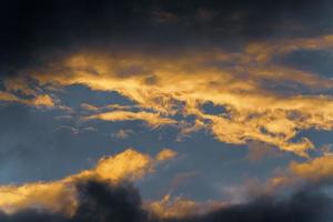 tormenta nubes iluminado por desapareciendo rayos a atardecer, nubes de tormenta flotante a través de soleado azul cielo a cambio temporada clima foto