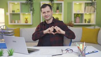 Home office worker showing his love by looking at camera gives trust and respect. Positive freelancer man expressing his love and trust while looking at camera at home working desk. video