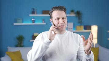 das Mann reden auf das Telefon beim Zuhause ist versuchen zu erklären sich selbst, er spricht ruhig und ohne Panik. das Mann reden auf das Telefon beim Zuhause ist erzählen etwas im ein Ruhe und entspannt Benehmen. video