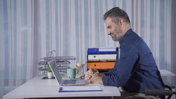 réussi homme d'affaire est dans bien esprits, réjouissance à bien nouvelles et gains. souriant mature homme d'affaire séance à le sien bureau dans le sien bureau, financier gains faire lui content, souriant à succès. video