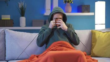 Man with sick and low body temperature at home. The man, shivering with cold, is sick, sipping hot herbal tea, and wants to regain his health. video
