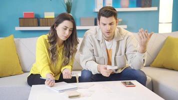joven marido y esposa plan el presupuesto. casado Pareja sentado en sofá a hogar leyendo débito tarjetas y calculador préstamo deuda pagos en línea. video