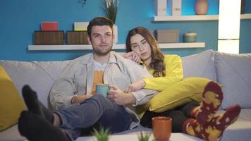 First date. Shy, young attractive lovers looking at each other, excited and happy. Happy and excited couple sitting on sofa at home, first date excitement and shyness. video