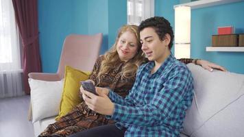 Mother son love. Mother son looking at phone and laughing. Happy and cheerful mother and son looking at funny videos on phone, looking at social media posts.