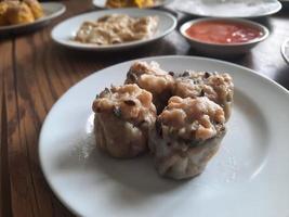 dimsum served warm on a white plate with sauce. photo