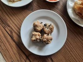 dimsum served warm on a white plate with sauce. photo