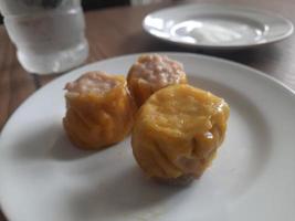 dimsum served warm on a white plate with sauce. photo