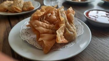 Pangsit, Pangsit Goreng, delicious Pangsit Ayam Goreng or Chicken Fried Dumpling, Indonesia Traditional Food made from flour and chicken, served on white sauce. photo