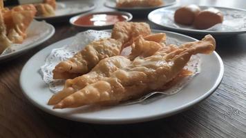 Pangsit, Pangsit Goreng, delicious Pangsit Ayam Goreng or Chicken Fried Dumpling, Indonesia Traditional Food made from flour and chicken, served on white sauce. photo