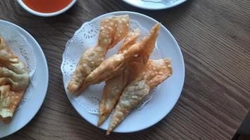 Pangsit, Pangsit Goreng, delicious Pangsit Ayam Goreng or Chicken Fried Dumpling, Indonesia Traditional Food made from flour and chicken, served on white sauce. photo