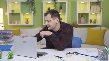 Single man suffering from loneliness is bored at home alone, tired of doing work. Unhappy and depressed man working on laptop alone at home, unhappy with his life. Motivation loss. video