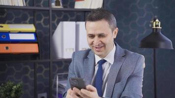 Smiling mature businessman holding smartphone in office.  Mature man using mobile phone mobile apps. Digital technology applications and solutions. video