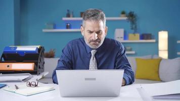 volwassen zakenman werken van laptop in huis kantoor zien slecht nieuws, verveeld, boos. volwassen zakenman krijgen depressief terwijl lezing frustrerend nieuws terwijl werken Aan laptop. video