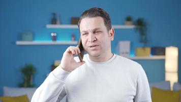 Adult man talking on the phone in a cheerful and serious manner. The man talking on the phone at home is trying to tell his happy memory, talking calmly and without panic, laughing and having fun. video