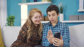 The smart mobile phone, which is a technology tool, is in the young man's hand and the young man is telling his mother how to use it. video