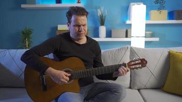 Bored of loneliness, the man is overwhelmed and unhappy at home. The man who suffers in despair and loneliness, the man who plays the guitar in his house is devastated in unhappiness. video