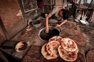 un antiguo vendedor de venta horneado naan en el antiguo calle de kashgar foto