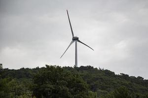 Wind turbine behind an old house. Wind turbine on blue sky. photo