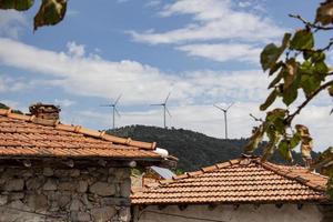 Wind turbines behind an old house. Wind turbines on blue sky. photo