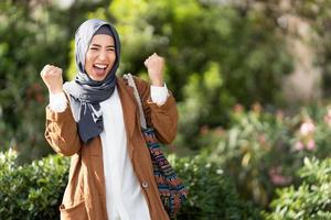 Muslim woman raising the fits to celebrate in a park photo