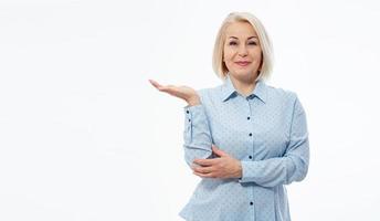 Photo of happy woman standing isolated over white wall background. Looking camera showing copyspace pointing.