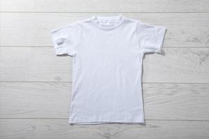 Front views on boys t-shirts on white wooden desk background. Mockup for design closeup photo