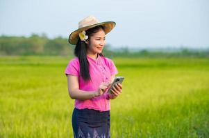 Asian female farmer holding tablet walking in rice field to store information photo