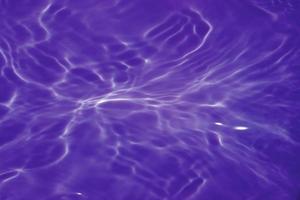 Defocus blurred transparent purple colored clear calm water surface texture with splashes and bubbles. Trendy abstract nature background. Water waves in sunlight with copy space. Purple velvet. photo