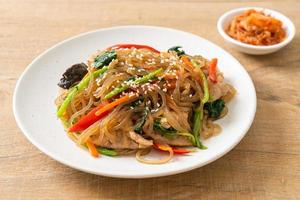 japchae or stir-fried Korean vermicelli noodles with vegetables and pork topped with white sesame photo